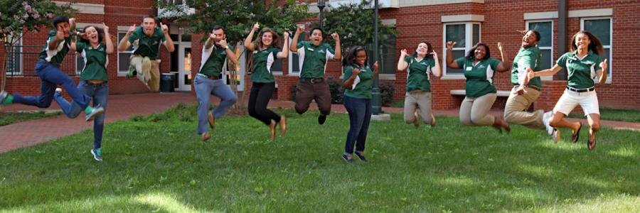 A group of people in UNC Charlotte shirts jumping in the air 