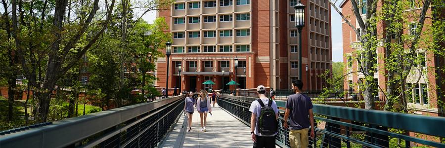 Students walking on campus across bridge