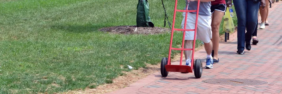 A person pushing an empty hand truck, moving in