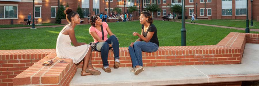 3 students sitting around campus socializing