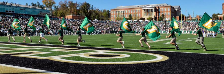 Multiple students running across football field with flags