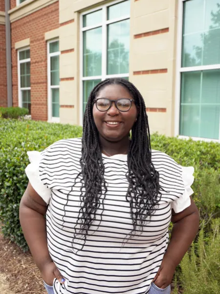 Audri Womble smiling outside in a black-and-white striped shirt