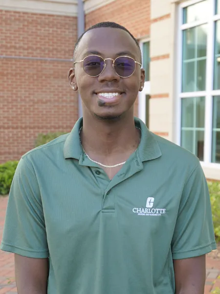 Justyn Ramseur smiling outside with sunglasses and a green polo