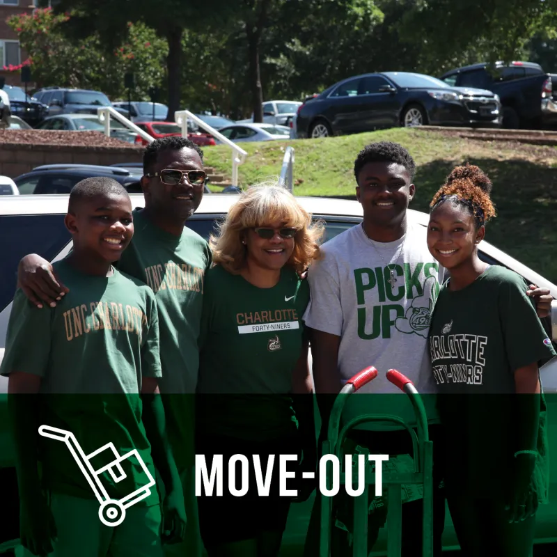 Image of 5 family members with a hand truck moving boxes into a residence hall
